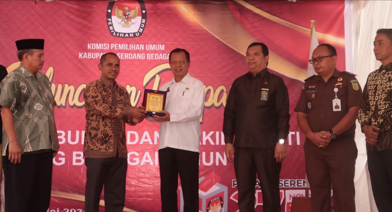 Ketua KPU Sergai Agusli Matondang saat memberikan penghargaan kepada Pemkab Sergai diterima Staf Ahli Bupati Zulfikar di sela peluncuran tahapan Pemilihan Bupati dan Wakil Bupati Sergai tahun 2024, Rabu (8/5) di halaman kantor KPU Sergai di Desa Firdaus Kec.Sei Rampah.(Waspada/Edi Saputra)