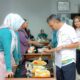 Manager PLN UP3 Bukit Barisan sedang mencicipi dan menilai hasil masakan peserta lomba memasak menggunakan kompor induksi.