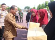 Pj Bupati Aceh Timur Ir Mahyuddin, M.Si, didampingi Kapolres Aceh Timur AKBP Nova Suryandaru SIK, menyerahkan sembako murah di Lapangan Polres Aceh Timur, Selasa (25/6). Waspada/H. Muhammad Ishak