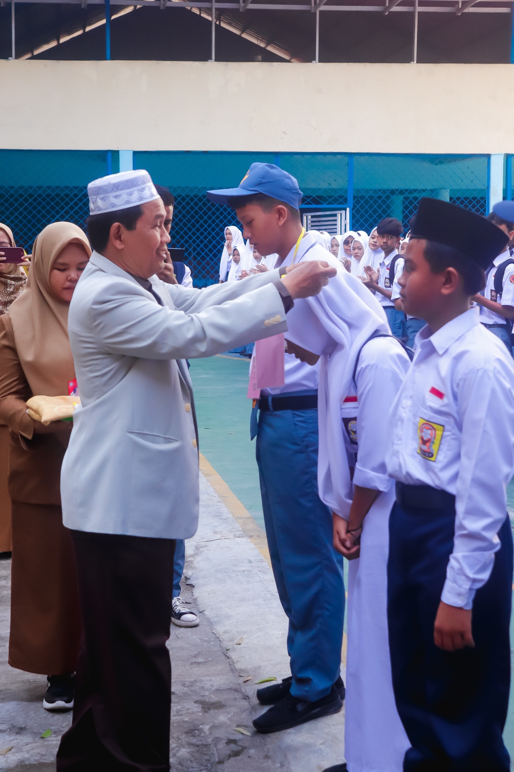 Ketua Yayasan Perguruan Istiqlal Delitua Prof. Dr. Jumino Suhadi, MA memasangkan tanda peserta MPLS kepada siswa Mts, SMP, SMA dan SMK Istiqlal. Waspada/Ist