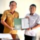 Kepala Dinas PMD Nias Utara A'aro'o Zalukhu, S.Pd.,M.M (kiri) menyerahkan data perangkat desa di wilayah Nias Utara kepada Kepala Cabang BPJS Ketenagakerjaan Nias Gunung Sitoli, Tunggul Rinton Mardo S di Kantor PMD Nias Utara, Selasa (9/7). Waspada/ist.
