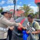 Kasat Lantas Polres Pematangsiantar AKP Gabriellah A Gultom bersama personelnya membagikan nasi bungkus kepada seorang penyandang disabilitas yang sehari-hari berjualan kaus kaki keliling saat Sat Lantas melaksanakan gerakan sosial kepada pengemudi becak bermotor, juru parkir, pedagang asongan dan lainnya.(Waspada-Ist).