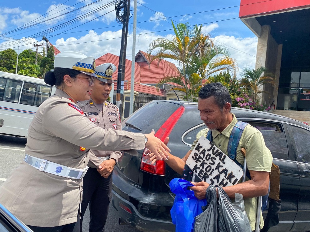 Kasat Lantas Polres Pematangsiantar AKP Gabriellah A Gultom bersama personelnya membagikan nasi bungkus kepada seorang penyandang disabilitas yang sehari-hari berjualan kaus kaki keliling saat Sat Lantas melaksanakan gerakan sosial kepada pengemudi becak bermotor, juru parkir, pedagang asongan dan lainnya.(Waspada-Ist).