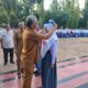 Kepala SMKN 1 Percut Seituan Usman Siregar, ST, menyematkan badge dan topi kepada salah seorang siswi pada upacara PLS Tahun Ajaran 2024/2025 di halaman sekolah tersebut, Selasa (16/7). (Waspada/Khairul K Siregar/B)