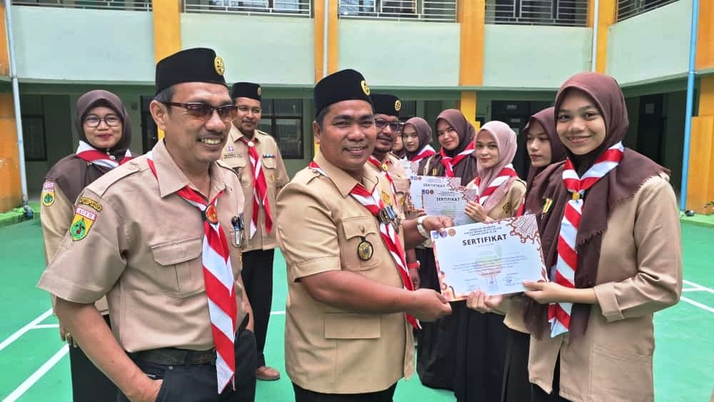 Doktor Emi menyerahkan sertifikat dan penyematan Tiska Kemsama (Kemah Bersama) Pramuka se-Aceh - Sumatera Utara tahun 2024 yang dilaksanakan Gudep Kota Langsa, dari Mabigus Kota Langsa kepada para Pramuka FTIK IAIN Langsa, Senin (1/7). Waspada/dede