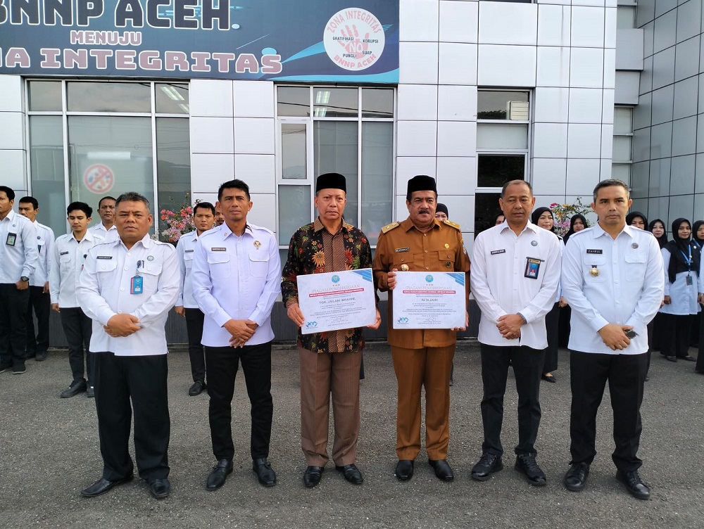 Kepala BNN Provinsi Aceh Marzuki Ali Basyah didampingi Kepala BNN Kota Banda Aceh Zahrul Bawadi menyerahkan penghargaan kepada dua orang Keuchik (Kades) di Banda Aceh dan Aceh Besar di halaman Kantor BNN Aceh, Rabu (24/07/24).(Waspada/T.Mansursyah)