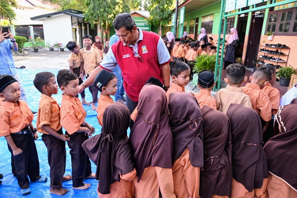 Kadisdikbud Aceh Besar, Bahrul Jamil berbincang akrab dengan murid baru saat memantau hari pertama sekolah di SD 1 Darul marah, Aceh Besar, Senin (15/7) lalu. (Waspada/Ist)