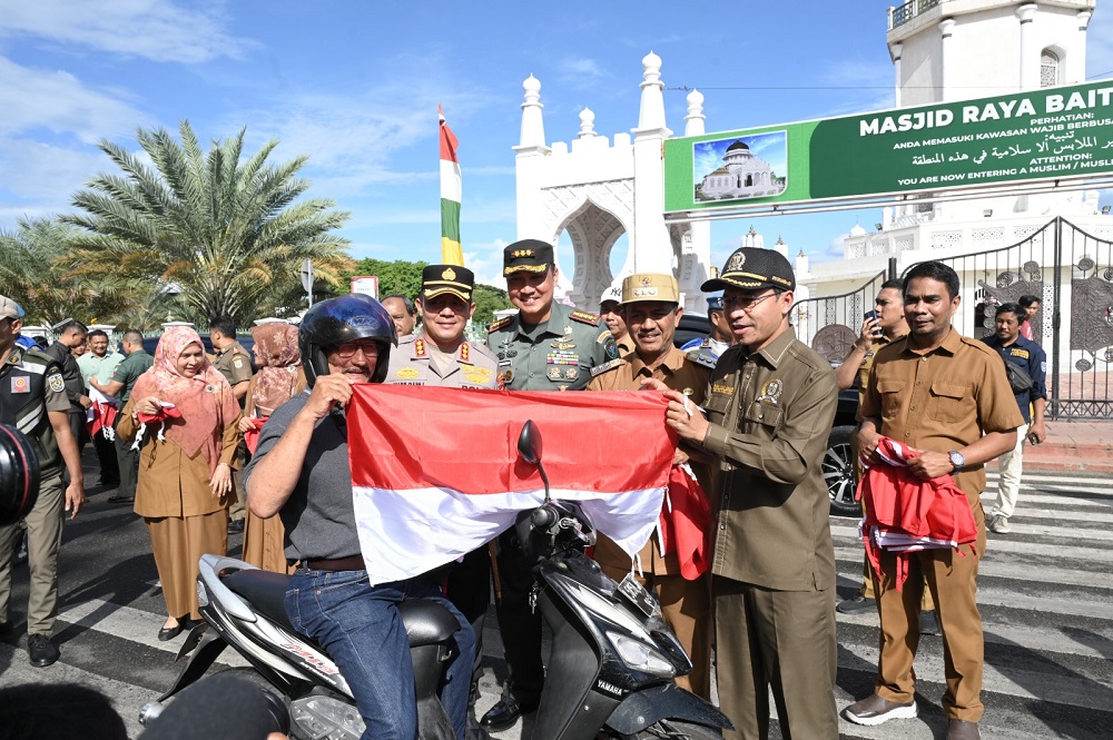 Ketua DPRK Banda Aceh Farid Nyak Umar bersama Forkopimda membagikan Bendera Merah Putih kepada pengguna jalan yang melintasi Kota Banda Aceh, Selasa (06/08/24).(Waspada/T.Mansursyah)