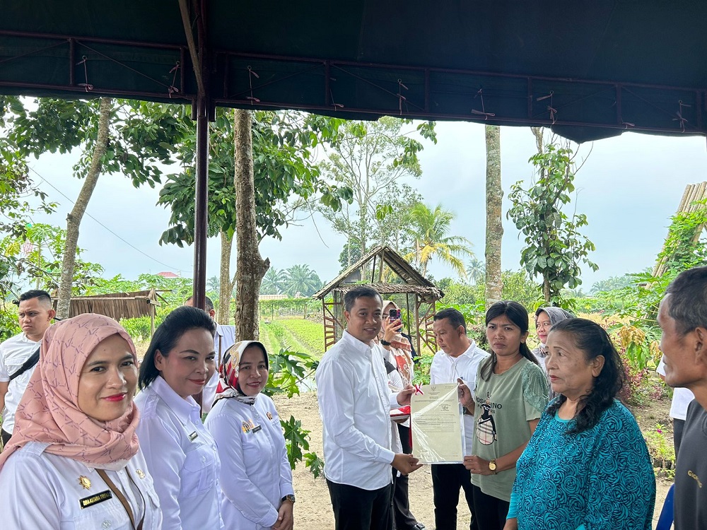 Pj Wali Kota Tebingtinggi, Dr Moettaqien Hasrimi, S.STP, M.Si didampingi Kepala Kantor ATR/BPN Kota Tebingtinggi, Yayuk saat menyerahkan sertifikat tanah kepada petani di Kecamatan Bajenis. Waspada/Kristian Brahmana