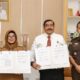 Wali Kota Susanti Dewayani (kiri) dan Kajari Jurist Precisely Sitepu (kanan) saling menunjukkan nota kesepakatan bersama Pemko dan Kejari Pematangsiantar usai mereka tanda tangani di ruang kerja wali kota di lantai dua Balai Kota, Jl. Merdeka, Senin (26/8).(Waspada-Ist).