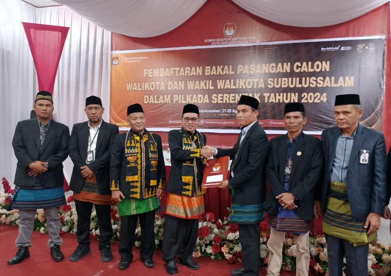 DIDAMPINGI Karlinus (tiga kiri), Fajri Munte menyerahkan berkas Paslon kepada Ketua KIP, Asmiadi. (Waspada/Ist)