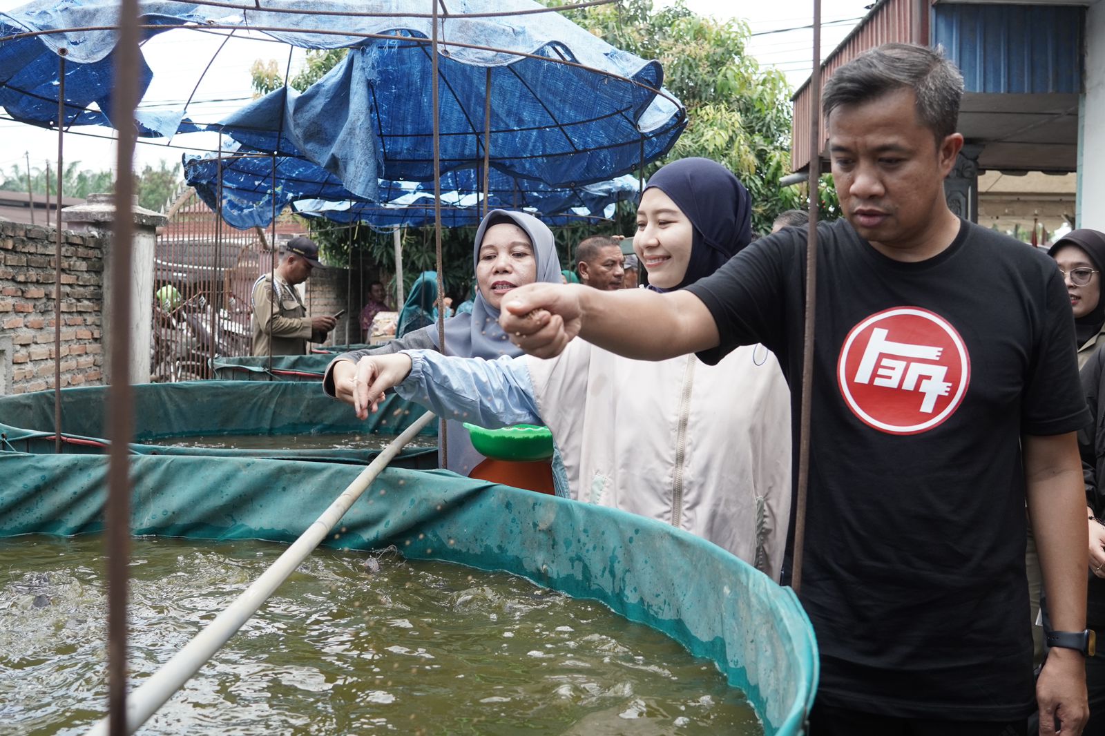 Pj Wali Kota Tebingtinggi, Dr Moettaqien Hasrimi, S.STP, M.Si bersama Pj Ketua TP PKK Kota Tebingtinggi, dr Dara Caprina saat memberikan makan ke kolam ikan milik kelompok ternak. Waspada/Ist