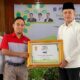 KETUA PW MES Sumut Musa Rajekshah memberikan penghargaan kepada JNE Medan diterima Fikri Alhaq Fachryana selaku Branch Manager JNE Medan pada acara Milad MES ke 24 di Pendopo Rumah Dinas Walikota Binjai. Waspada/ist