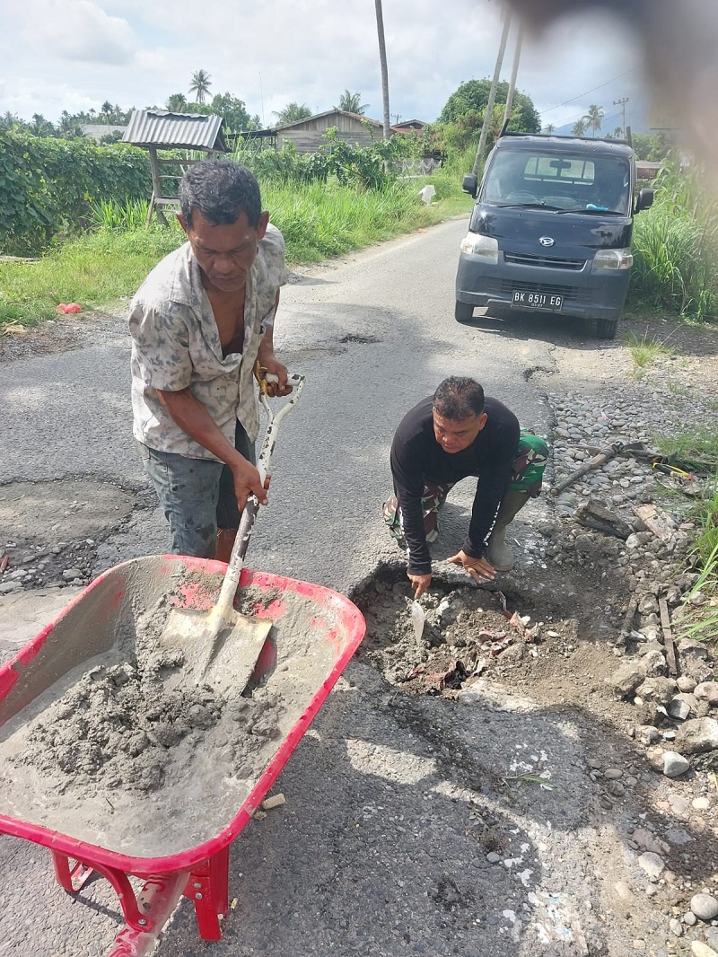 Sertu Syamsul Ibadi, Babinsa Kodim 0108/Agara saat sedang melaksanakan gotong royong memerbaiki jalan rusak bersama warga. Waspada/Seh Muhammad Amin
