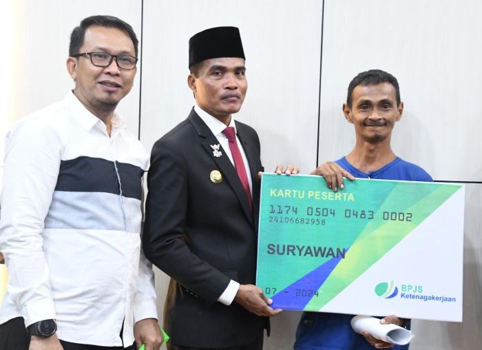 Pj Wali Kota Langsa, Dr (C) Syaridin SPd, MPd didampingi Kepala BPJS Ketenagakerjaan Kantor Cabang Kota Langsa, Muhammad Kurniawan saat menyerahkan kartu peserta BPJS Ketenagakerjaan di ruang kerja wali kota, Kamis (12/9). Waspada/ist