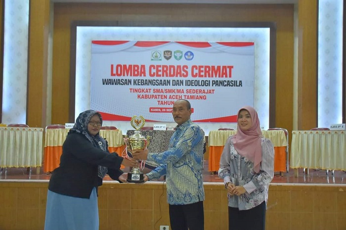 Pj Sekda Aceh Tamiang, Tri Kurnia saat menyerahkan tropi dalam kegiatan lomba cerdas cermat wawasan kebangsaan, Kamis (26/9) di aula SKB Karang Baru. (Waspada/Yusri).