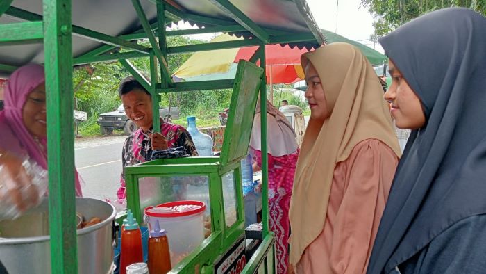 Cut Sauda (kiri), penjual bakso pentol di dekat pintu gerbang UIN Syahada Padangsidimpuan sedang melayani mahasiswa yang membeli bakso pentol dagangannya. Waspada/Mohot Lubis.