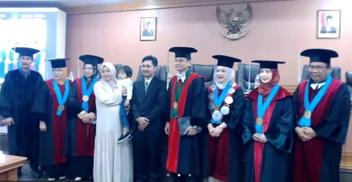 Dr Ilham Sahdi Lubis, MSi bersama istri (tengah) foto bersama dengan tim penguji usai menjalani sidang promosi doktor bidang ilmu linguistik di USU, Selasa (29/10). Waspada/ist.