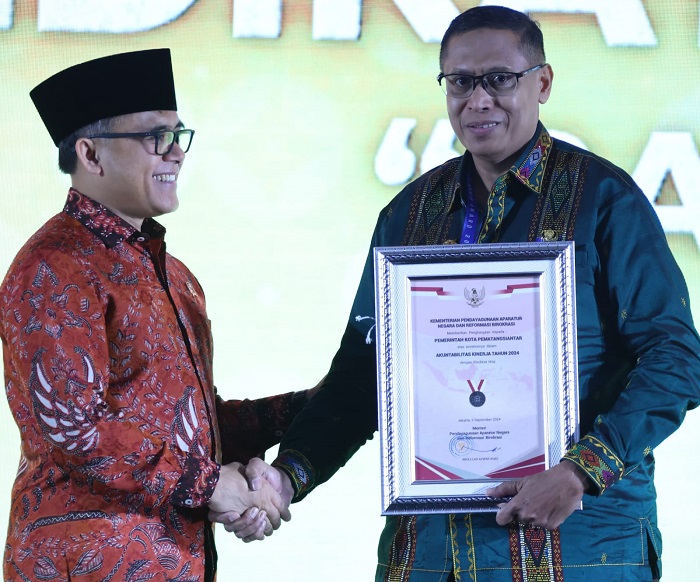 Pjs Wali Kota Pematangsiantar Matheos Tan (kanan) berjabatan tangan dengan Menteri PAN-RB Abdullah Azwar Anas (kiri) setelah menerima piagam penghargaan Sakip Award 2024 di Hotel Bidakara, Jakarta Selatan, Rabu (2/10).(Waspada-Ist).