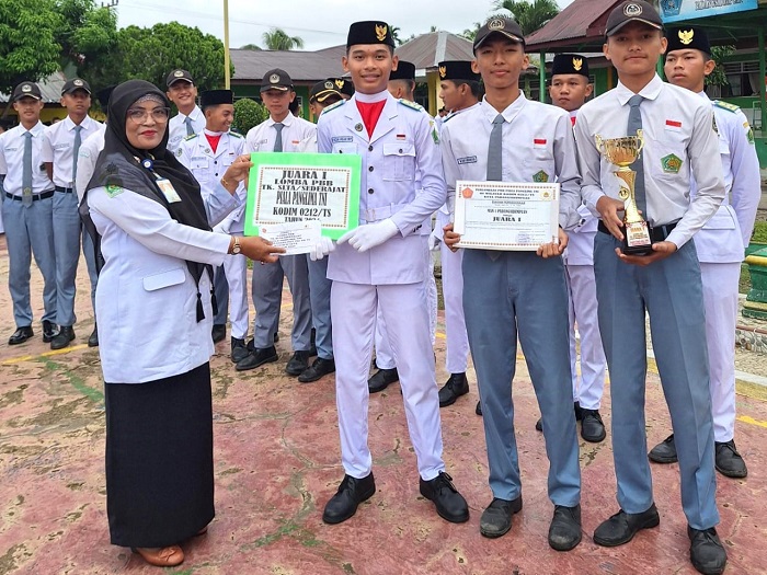 Kepala MAN 1 Padangsidimpuan Dra Hj Wasliah Lubis, SPd, MA, menyerahkan piagam penghargaan Juara 1 Lomba PBB Tingkat SMA sederajat se-Kota Padangsidimpuan yang di gelar Kodim 0212/TS dalam rangka memperingati HUT Ke-79 TNI Tahun 2024, Selasa (1/10/2024). Waspada/ist.