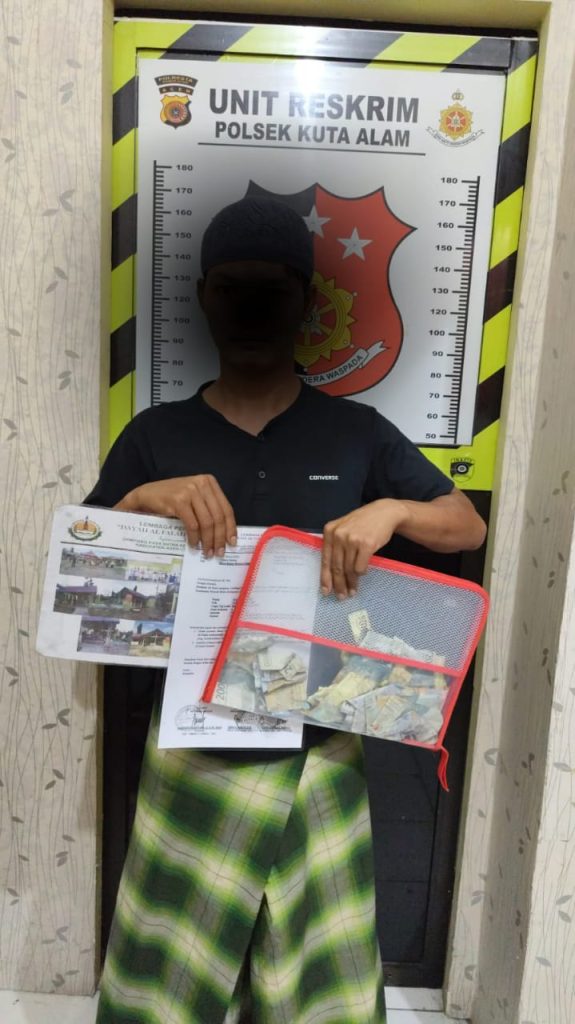 Tersangka AMR bersama barang bukti yang digunakan untuk mengutip sumbangan mengatasnamakan salah satu dayah di Aceh Utara, kini terpaksa mendekam dalam sel tahanan Polsek Kuta Alam Banda Aceh. (Waspada/Zafrullah)