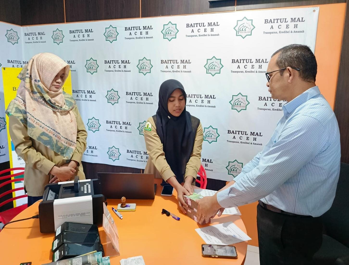 Direktur Kepatuhan, PT BPR Syariah Mustaqim Aceh, Muhammad Ali, (kanan) menyerahkan zakat karyawan sebesar Rp78 juta ke Baitul Mal Aceh, Senin (24/3/25).(Waspada/T.Mansursyah)