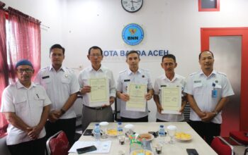 Kepala BNNK Banda Aceh Zahrul Bawadi (tengah) bersama Geuchik Gampong Ie Masen Kayee Adang dan Geuchik Gampong Pie memperlihatkan perjanjian gampong bersinar yang telah ditandatangani di Ruang Rapat Kantor BNNK Banda Aceh, Rabu (30/04/25).(Waspada/T.Mansursyah)