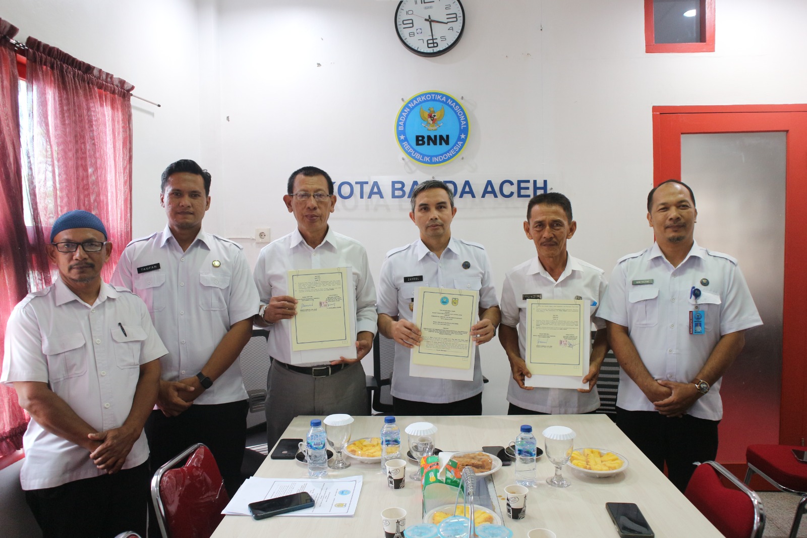 BNNK Banda Aceh Tanda Tangani Perjanjian Dua Gampong Bersinar Kepala BNNK Banda Aceh Zahrul Bawadi (tengah) bersama Geuchik Gampong Ie Masen Kayee Adang dan Geuchik Gampong Pie memperlihatkan perjanjian gampong bersinar yang telah ditandatangani di Ruang Rapat Kantor BNNK Banda Aceh, Rabu (30/04/25).(Waspada/T.Mansursyah)