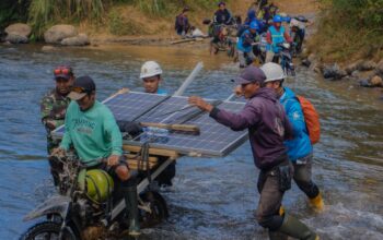 Petugas PLN bersama warga bahu-membahu membawa panel surya melintasi sungai. Upaya ini menjadi bagian dari perjalanan Program Listrik Desa (Lisdes) melalui SuperSUN dalam menghadirkan akses listrik bagi warga di Kecamatan Seko, Luwu Utara, Sulawesi Selatan.