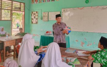 Syamsul Susidi Butar Butar, seorang guru MTs Negeri Batu Bara saat memberikan pelajaran menggunakan media pembelajaran kepada murid-muridnya.